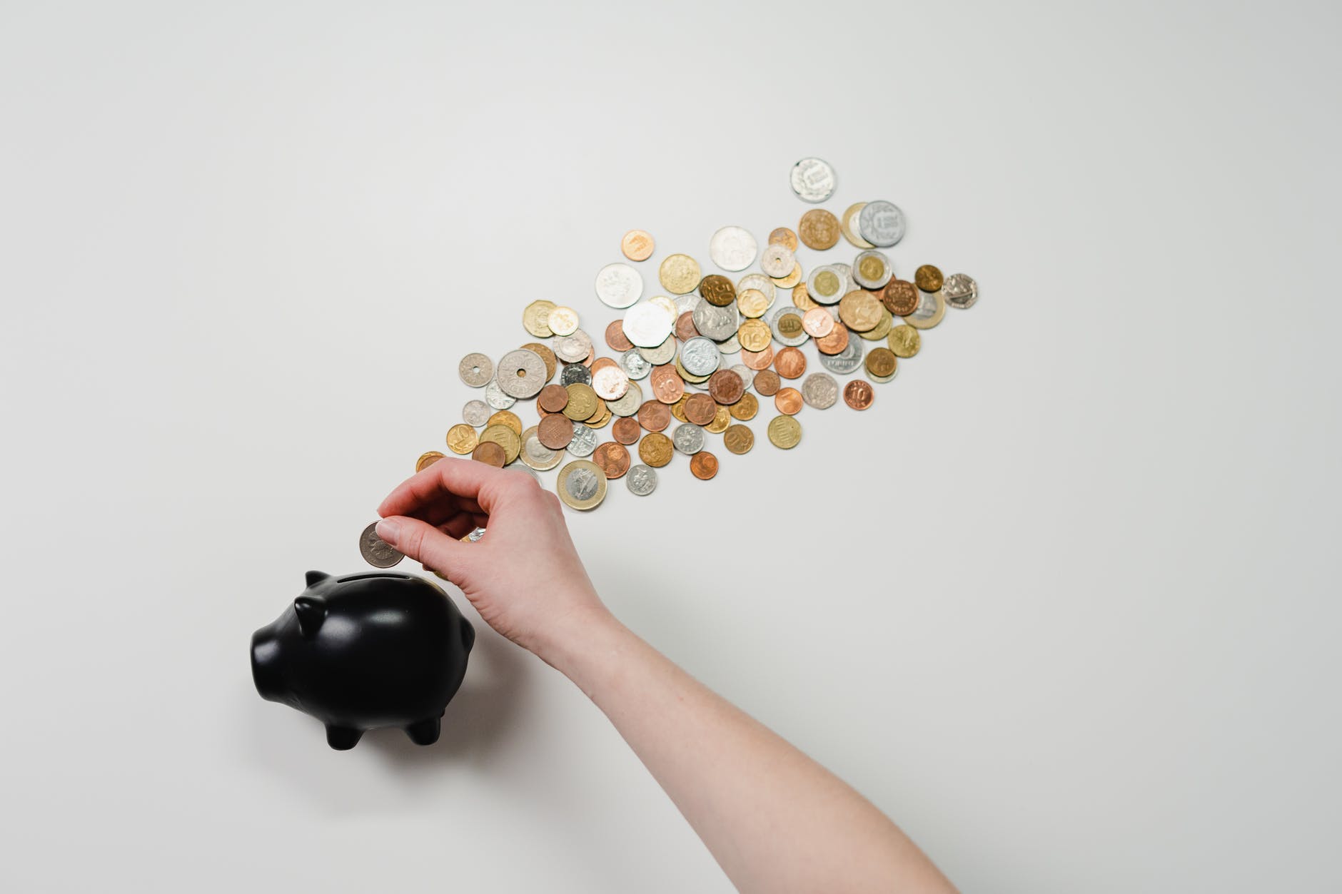 person putting coin in a piggy bank