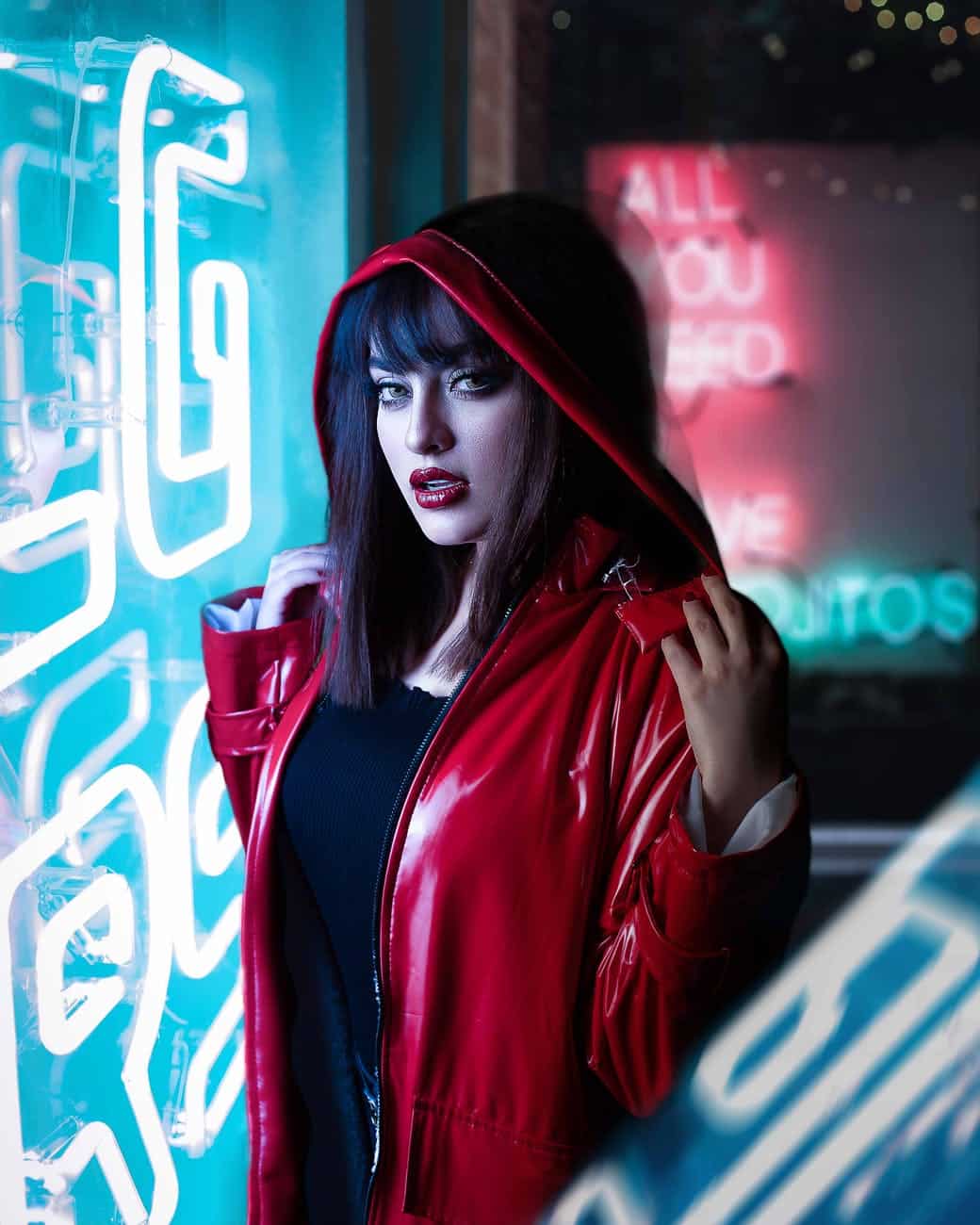 woman wearing red leather jacket standing near neon light wall