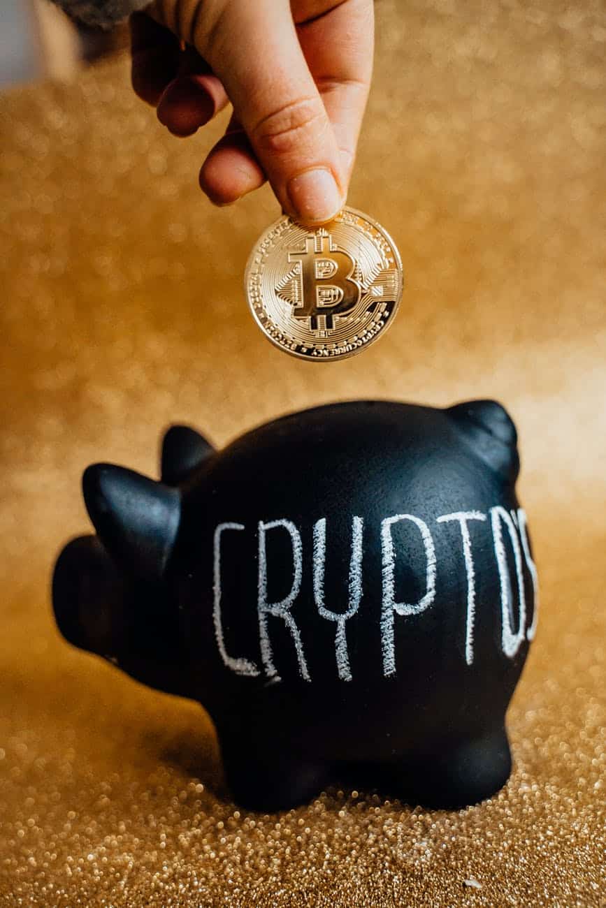 person putting bitcoin in a piggy bank