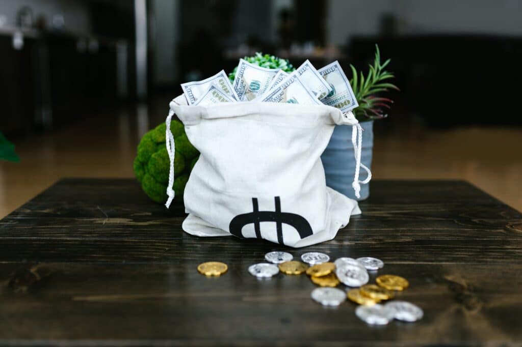 money on a tote bags and coins on the table to represent investing.