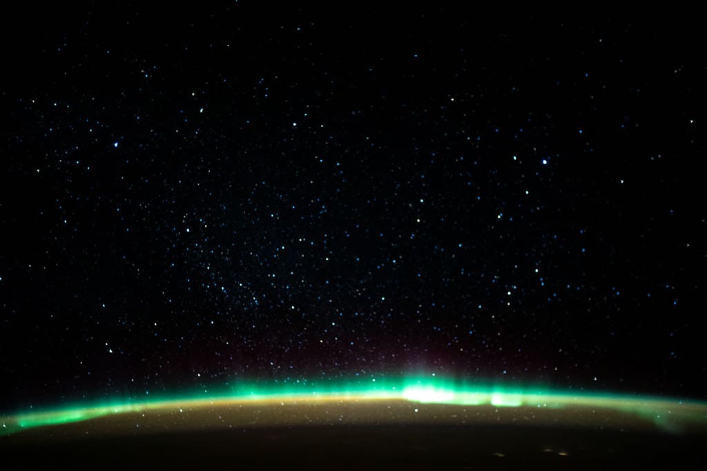 An aurora blankets the Earth beneath a celestial night sky