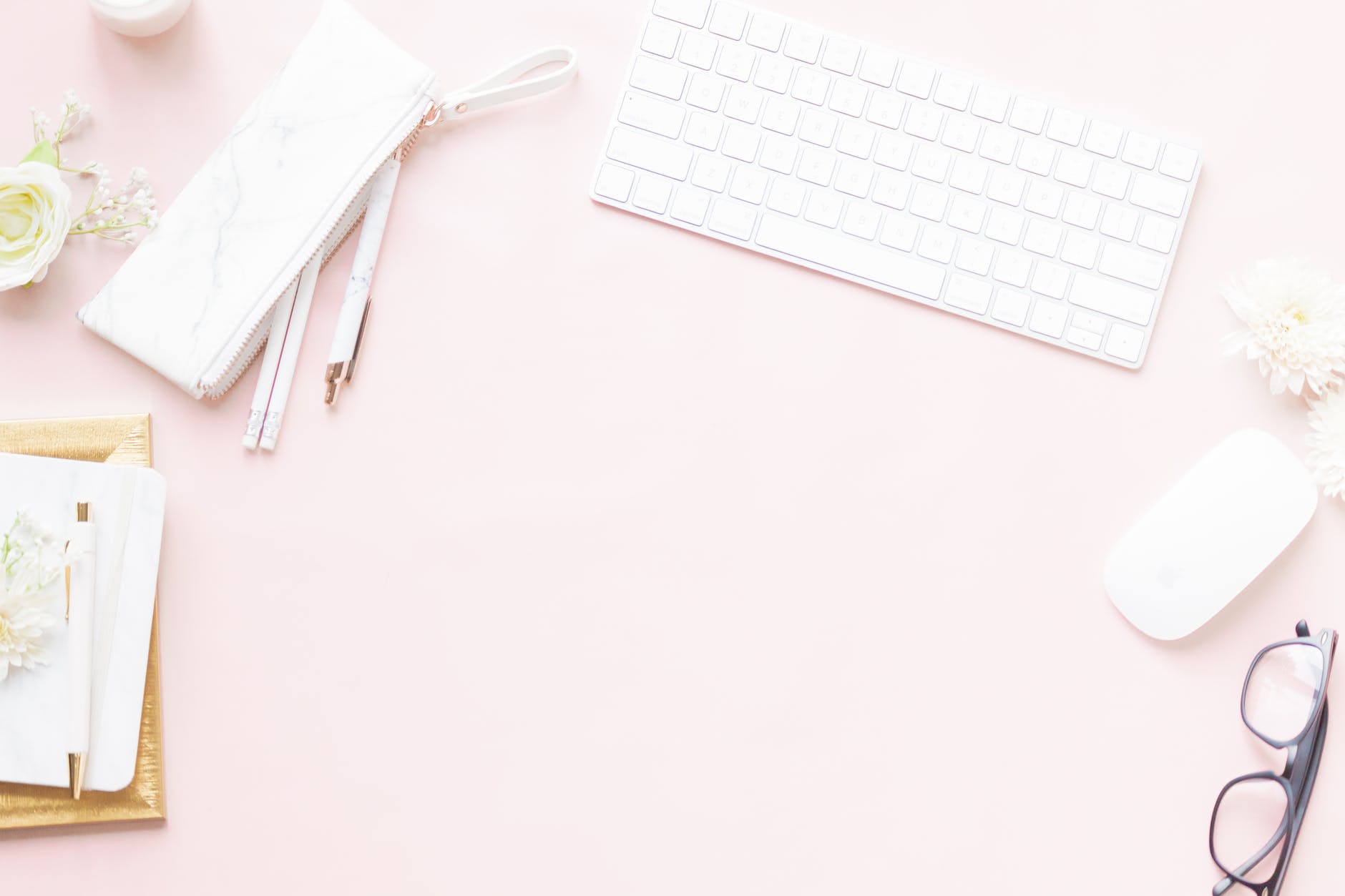 white keyboard and computer mouse beside pens and eyeglasses on pink surface