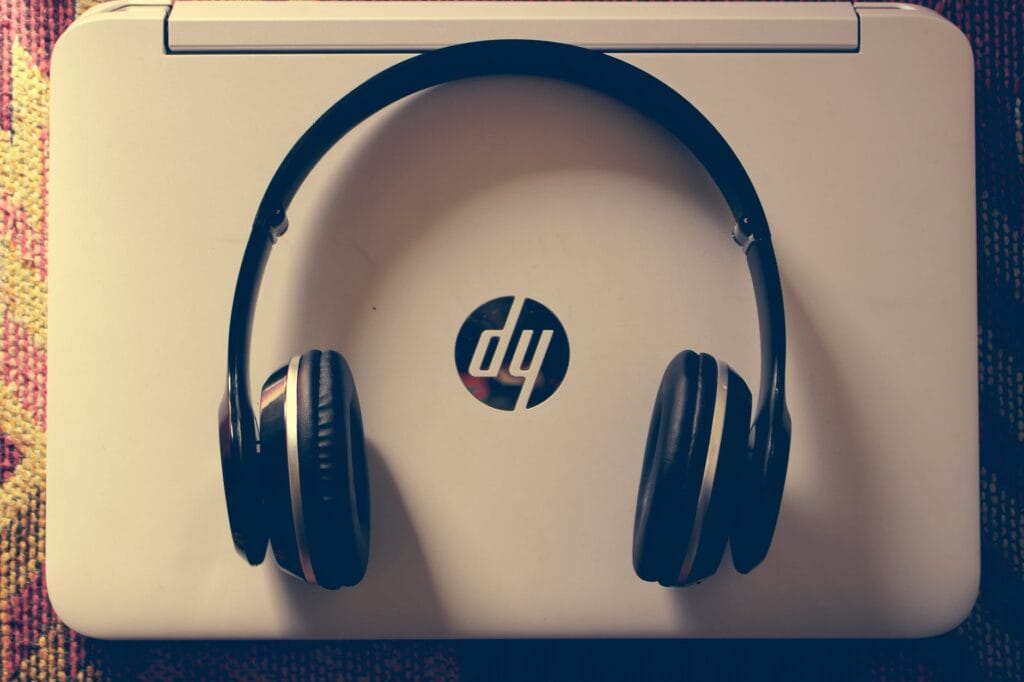 black wireless headphone near white hp laptop