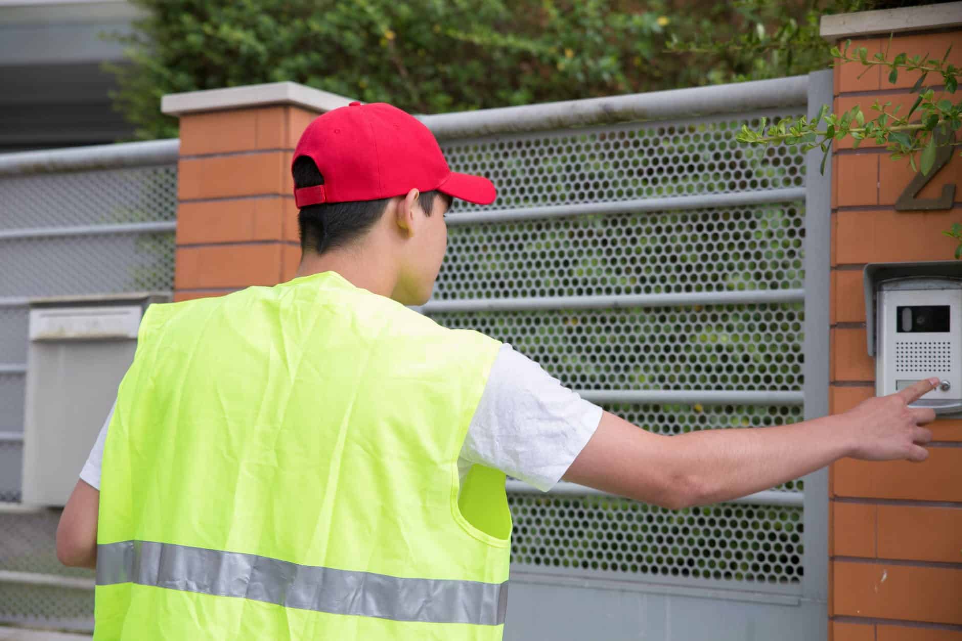 a delivery person ringing a doorbell at a gate