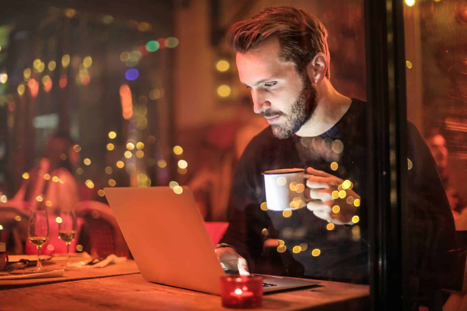 man holding mug in front of laptop