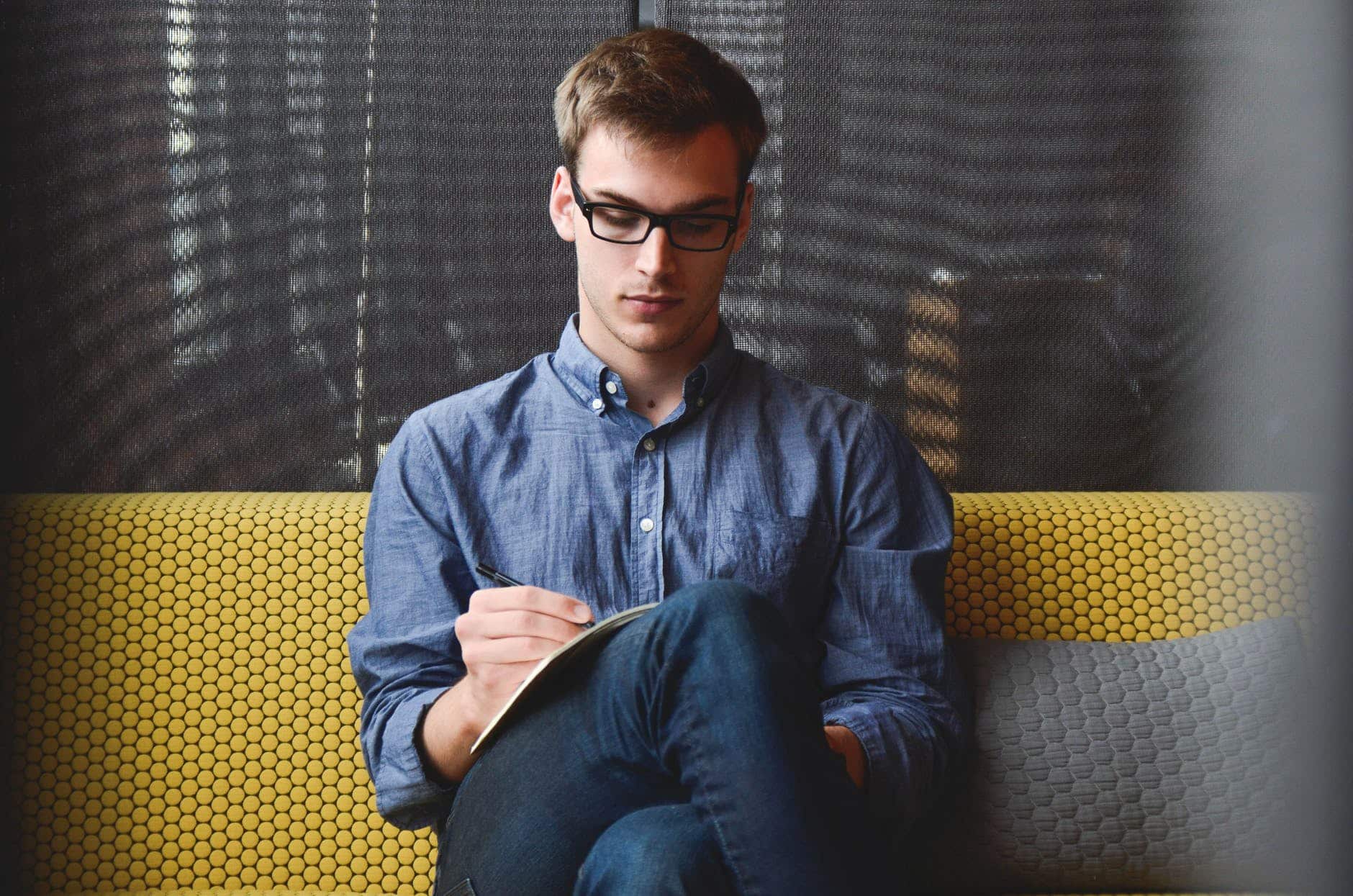 person in blue denim jacket sitting on chair while writing