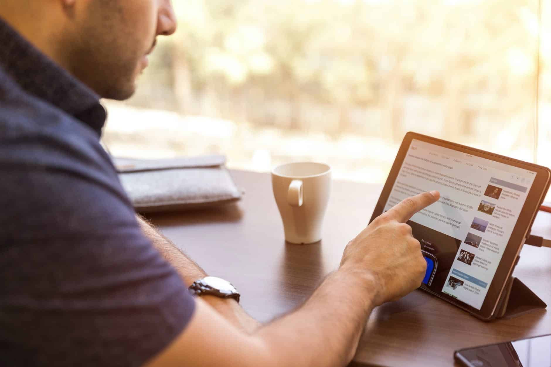 man using ipad sitting in front of desk