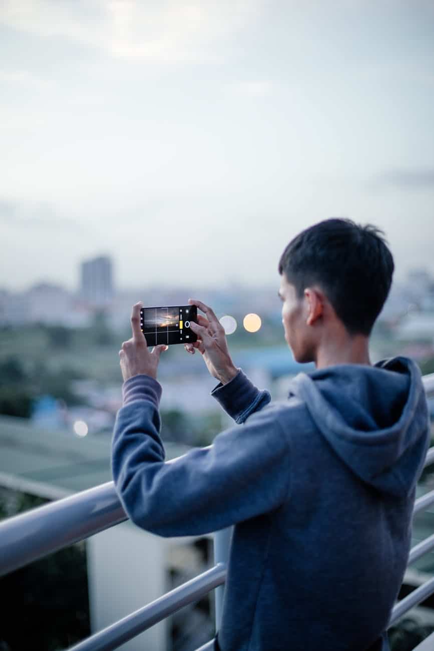 man in hoodie holding smartphone