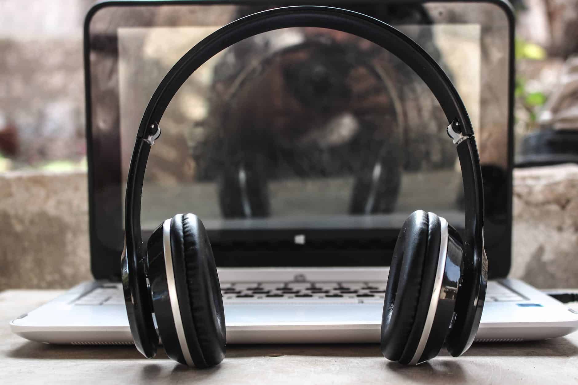 photo of black wireless headphones in front of the laptop