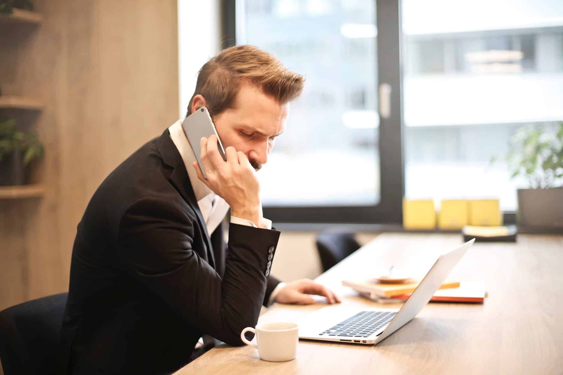 man having a phone call in front of a laptop