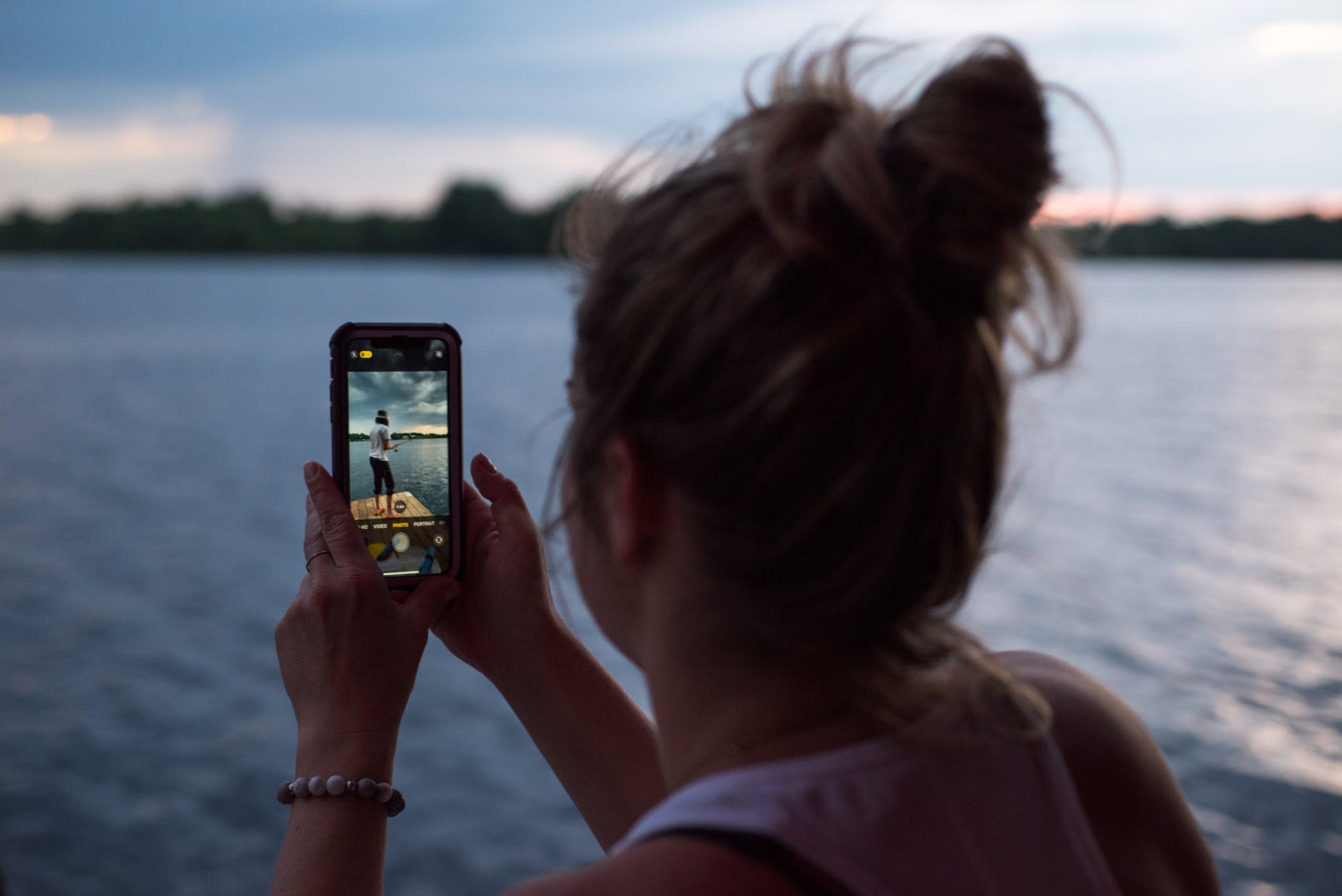 woman taking picture near water on mobile phone